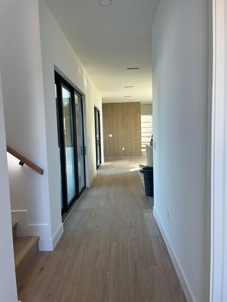 Hallway with wide-plank wood flooring, sliding glass doors, and a staircase, styled by Interior Painters in Tampa, FL.